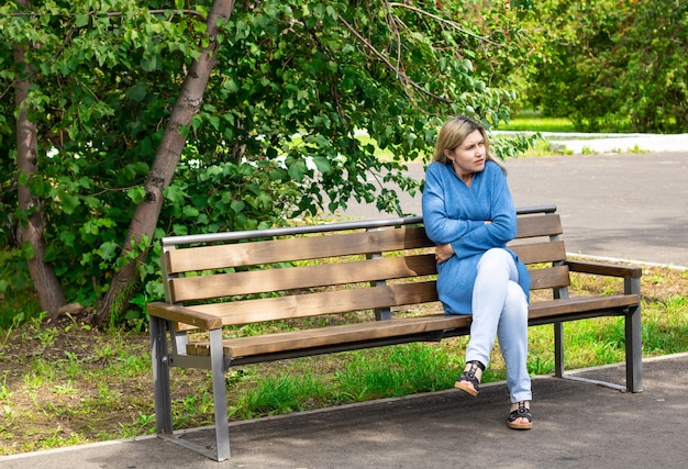 Cool day The woman on the bench is wrapping herself in a warm cardigan The woman froze Coldly