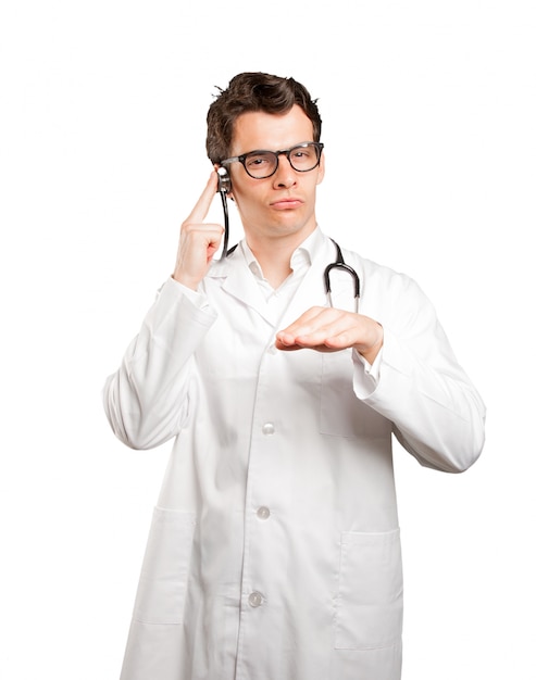 Cool doctor using a stethoscope against white background