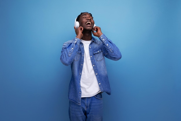 Cool dude american man with dreadlocks in a denim jacket relaxes to music in headphones