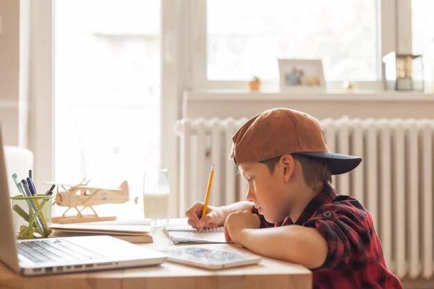 Photo cool elementary student doing his homework in the living room