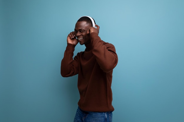 Cool energetic darkskinned american man with modern wireless headphones on the background with copy