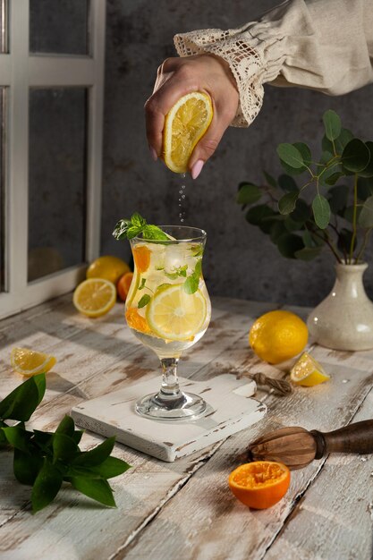 Cool freshly made lemonade in a tall glass Rustic style The girl's hand squeezes the juice