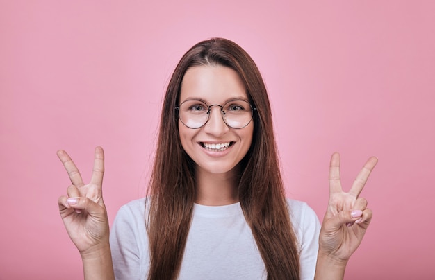 Cool girl smiling slightly and shows fingers peace