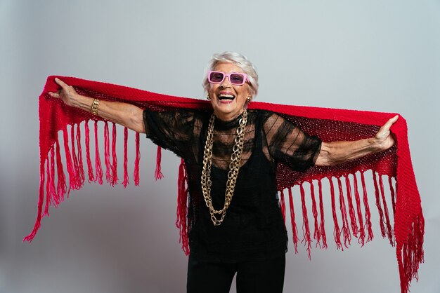 Cool grandmother posing in studio wearing fashionable clothes and making party