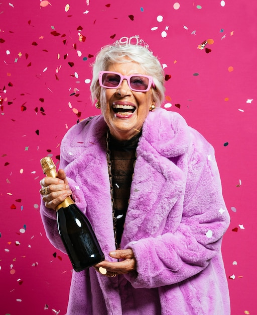 Cool grandmother posing in studio wearing fashionable clothes and making party