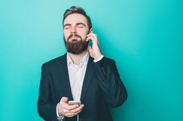 Cool guy is standing and listening to the music on the phone