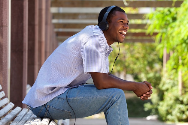 Cool guy laughing with headphones in park