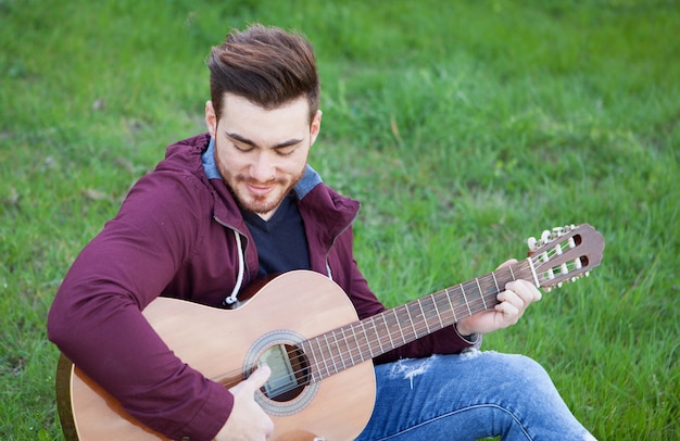 Cool handsome guy playing guitar at outside