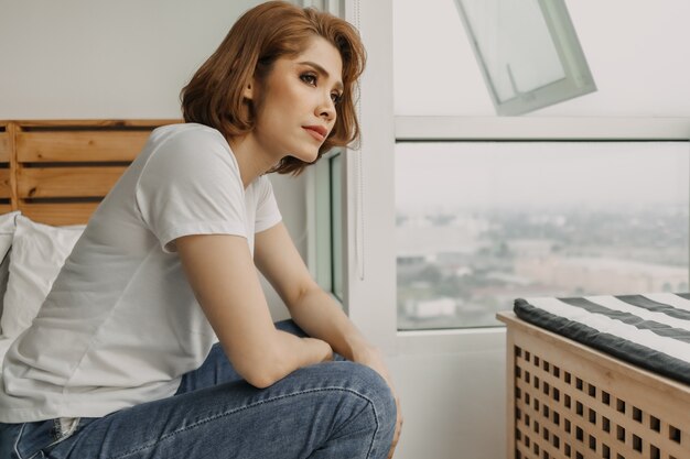 Cool looking woman is resting and watching view from her apartment