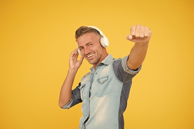 Cool man enjoy music his favorite playlist dj party happy man dancing yellow background listen to music in headphones catch the tune i like this track melody to dance sexy guy in disco mood