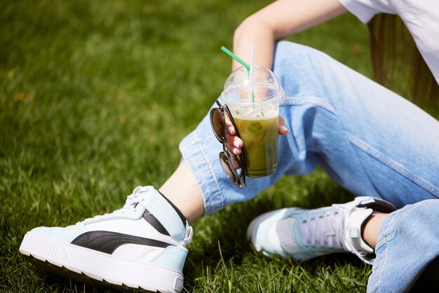 Cool matcha cocktail holds in hand on sky background with sunny weather