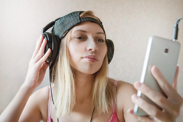 Cool meisje luistert naar muziek in koptelefoon op witte achtergrond Online videochat Communicatie Het maken van foto's van zichzelf het maken van selfies om een film te kijken op een smartphone audioboek