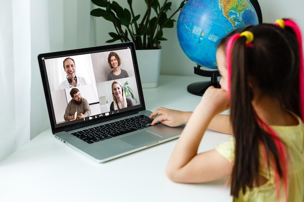 Cool online school. kid studying online at home using a laptop.
cheerful young little girl using laptop computer studying through
online e-learning system. distance or remote learning