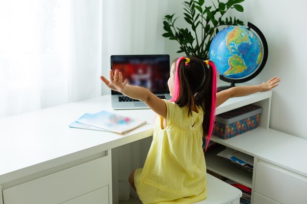 Cool online school. kid studying online at home using a laptop.
cheerful young little girl using laptop computer studying through
online e-learning system. distance or remote learning