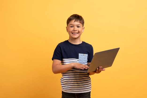 Photo cool preteen cute boy holding laptop computer and smiling
