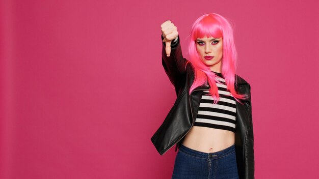 Cool punk woman showing thumbs down sign in studio