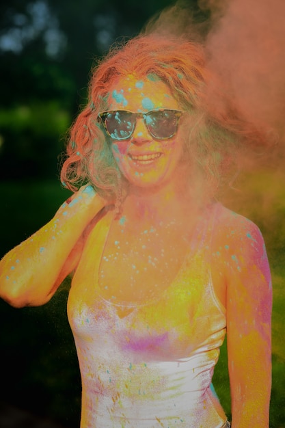 Cool redhead model having fun in a cloud of orange dry paint, at the Holi colors festival
