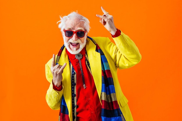 Фото Прохладный пожилой мужчина в модном стиле одежды портрет на цветном фоне - смешной старый мужчина пенсионер с эксцентричным стилем веселится
