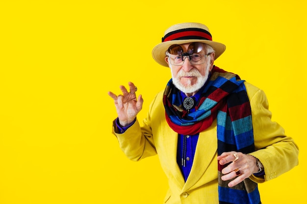 Фото Крутой пожилой мужчина с портретом в модном стиле одежды на цветном фоне забавный старый пенсионер с эксцентричным стилем веселится