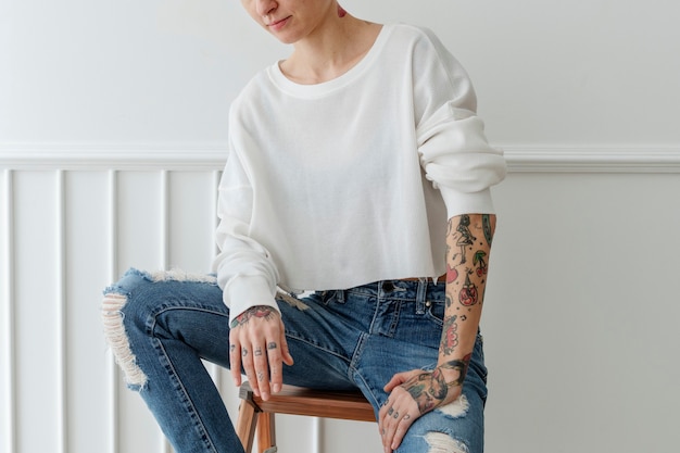 Bella donna tatuata con i capelli corti in jeans strappati