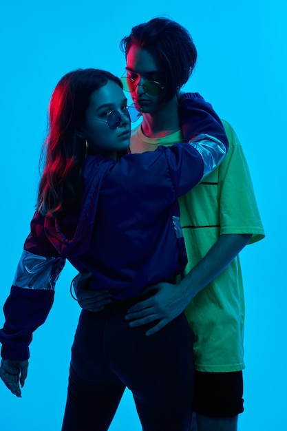 Cool teenage couple in dark studio with neon light