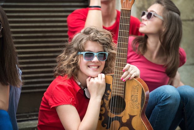 Foto adolescente freddo che propone con la chitarra