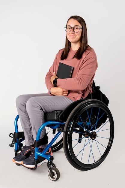 Foto bella donna su una sedia a rotelle con un libro nero