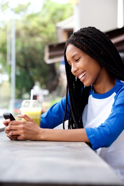 屋外のカフェでスマートフォンを使用して涼しい若いアフリカの女の子