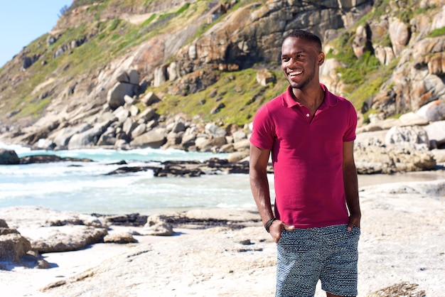 Photo cool young african guy smiling at the beach