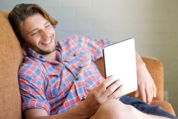 Cool young man sitting on sofa with tablet