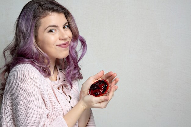 Cool young model with purple hair enjoying tasty dessert with berries. Space for text