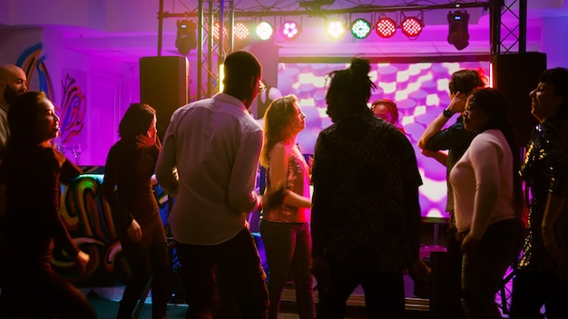Coole dansers die danspasjes laten zien op funky beats, plezier maken met mensen op sociale bijeenkomsten in discotheek. Groep mensen genieten van feest op de dansvloer, feest. Schot uit de hand.