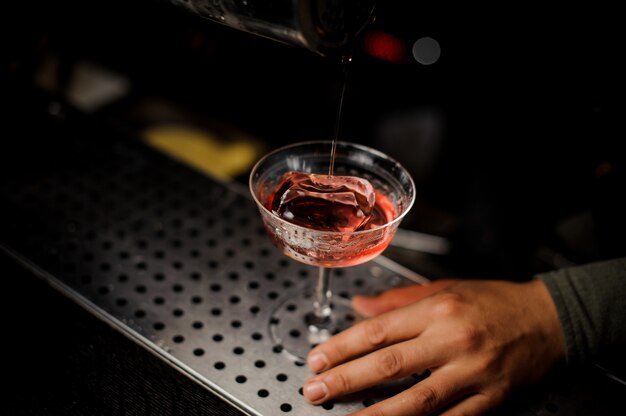 Cooled red cocktail with an ice on the barstand