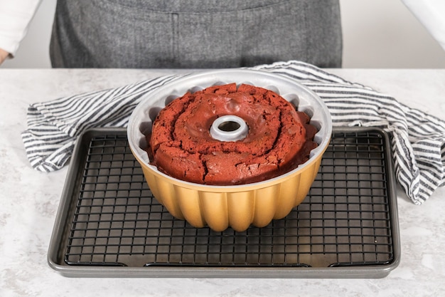 Cooling freshly baked red velvet bundt cake on a kitchen drying rack.