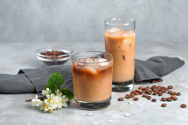 Cooling iced coffee in two glasses on a gray wall. The side view is horizontal.