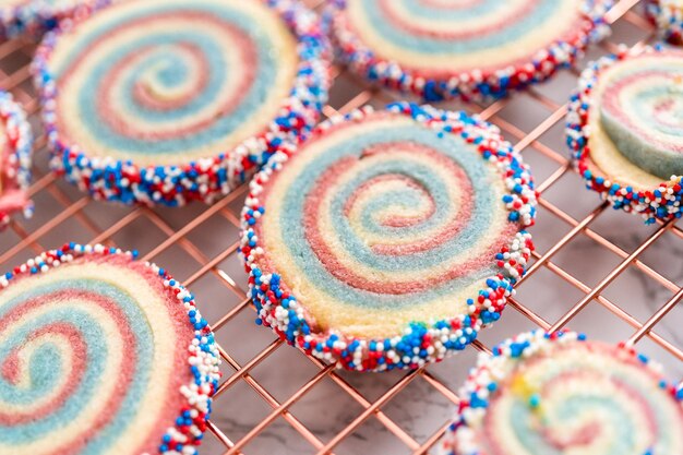 Foto biscotti di zucchero a girandola rossi, bianchi e blu di raffreddamento su una griglia di raffreddamento. dessert per la celebrazione del 4 luglio.