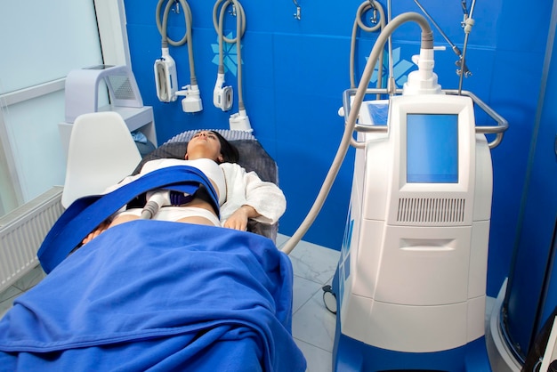 Coolsculpting procedure in cosmetology clinic girl patient lies on couch connected to the machine