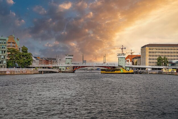 Copenhagen, Denmark. August 10, 2021. Beautiful canals of Copenhagen, the capital of Denmark. Magical summer view of Copenhagen city narrow streets, buildings, pedestrian bridges at sunset.