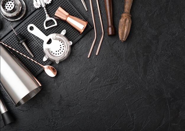 Photo copper bar spoon with straw and jigger on rubber bar tray with stainless steel shaker and strainer