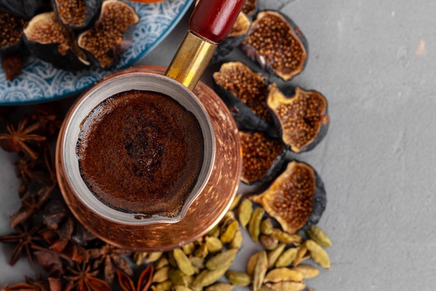 Copper coffee turk with dried seeds and fruits on grey surface