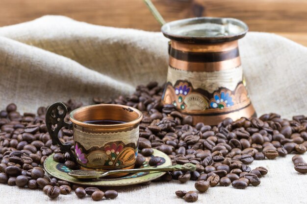 Copper colorful cup and cezve with coffee beans.