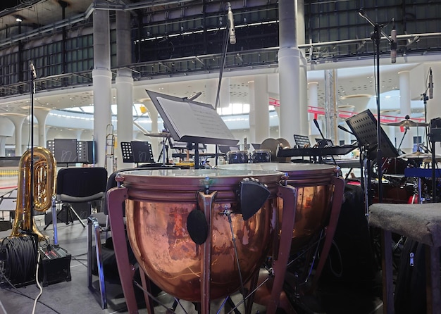 Photo copper drums with band or orchestra instruments and empty chairs arranged ready for a recital or concert in a close up view