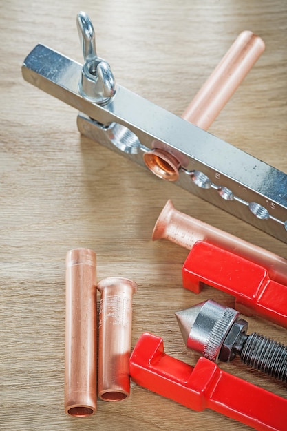 Copper flared pipes flaring clamp brake plumber on wood board top view.