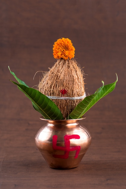 木製のテーブルに花の装飾が施されたココナッツとマンゴーの葉と銅カラッシュ。ヒンドゥー教のプージャーで不可欠です。