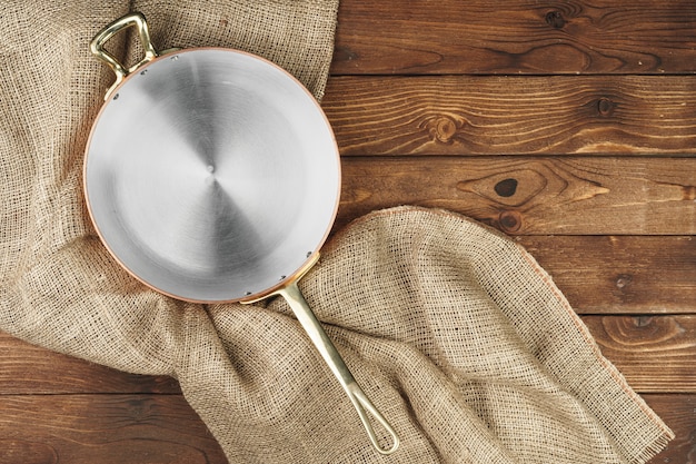 Copper pot on the dark wooden table, top view