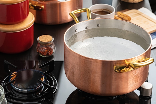 Copper pot with boiling water on a gas stove close up