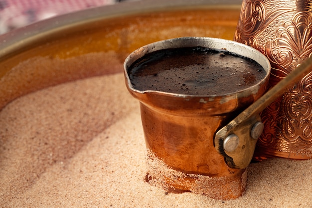 Copper turk with coffee brewing in sand