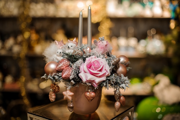 Copper vase with christmas decor composition of fir-tree branches, pink flower and ball ornaments