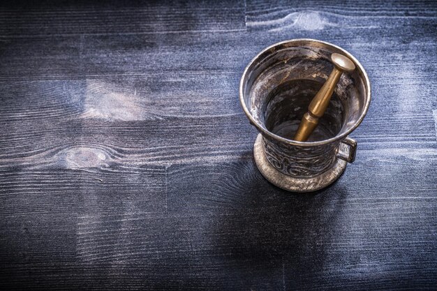 Photo coppery mortar and pestle on wooden surface