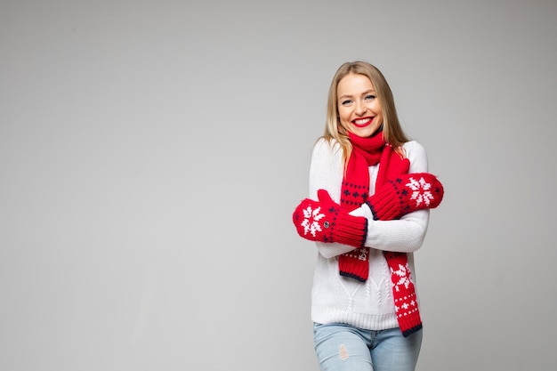 Coppy-space foto van een vrolijke jonge dame in gebreide trui en wanten die over haar schouders wrijft en glimlacht. Ruimte kopiëren